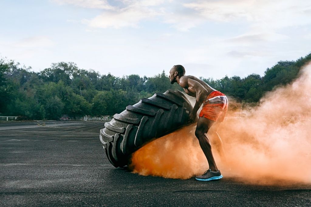 muscular man flipping big tire outdoors